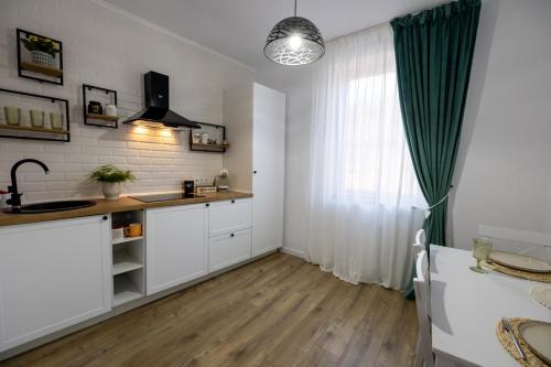 a kitchen with white cabinets and a green curtain at Cozy Studio in Sibiu
