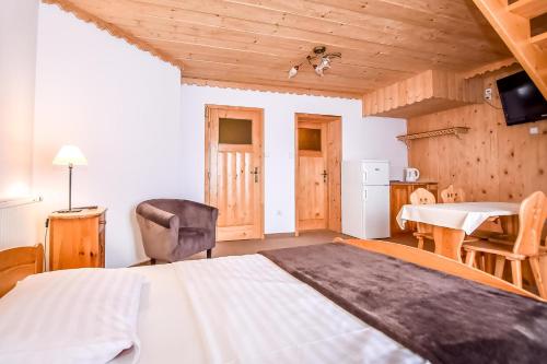 a bedroom with a bed and a table and a chair at Willa Pod Orłem Jacuzzi Sauna in Kościelisko