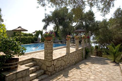 a retaining wall next to a swimming pool with potted plants at Nikatsas Cottage No 1 in (( Kerasá ))