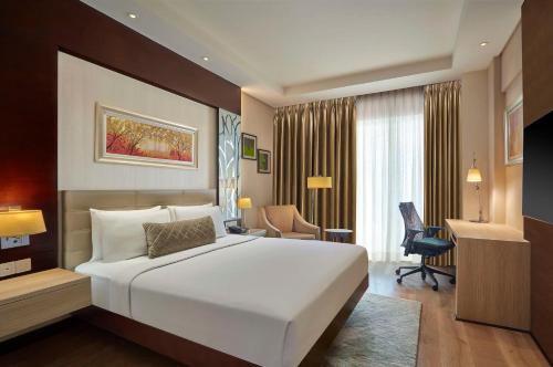 a bedroom with a large white bed and a desk at DoubleTree by Hilton Gurugram Baani Square in Gurgaon