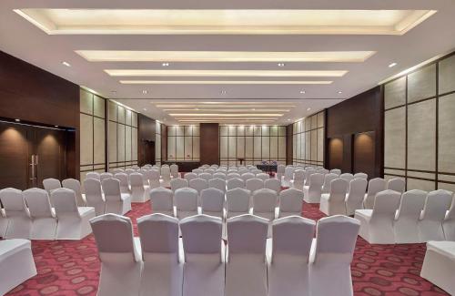 a conference room with white chairs and tables in it at DoubleTree by Hilton Gurugram Baani Square in Gurgaon