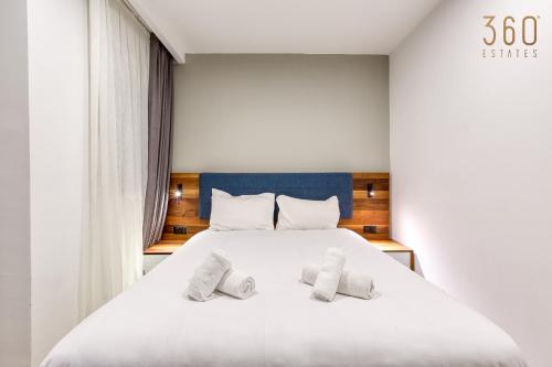 a bedroom with a large white bed with two pillows at The Swieqi Poolside Suites in Is-Swieqi