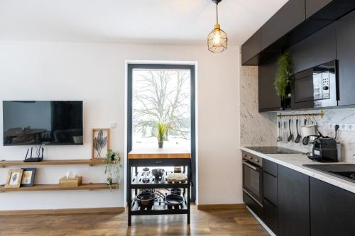 a kitchen with black cabinets and a window at Panorama Chlum Resort - Apartmán 2kk, 701 in Volary