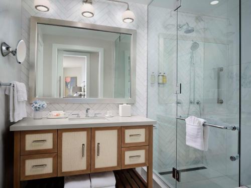 ein Bad mit einer Dusche, einem Waschbecken und einem Spiegel in der Unterkunft Shore House at The Del, Curio Collection by Hilton in San Diego