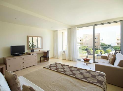 a living room with a couch and a desk with a television at The Ixian Grand & All Suites - Adults Only Hotel in Ixia