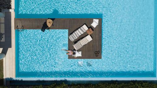 Een man en een vrouw op een steiger in een zwembad bij The Ixian Grand & All Suites - Adults Only Hotel in Ixia