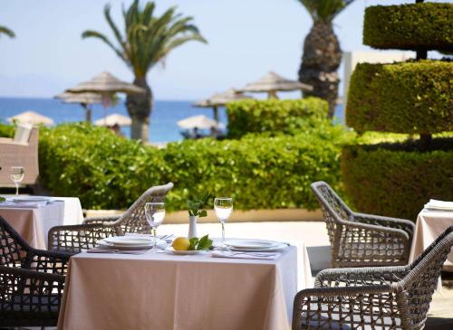a table with chairs and wine glasses and the ocean at The Ixian Grand & All Suites - Adults Only Hotel in Ixia