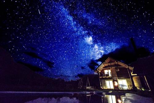 a starry night with a house and the milky way at Exo Log Cottage in Jezero