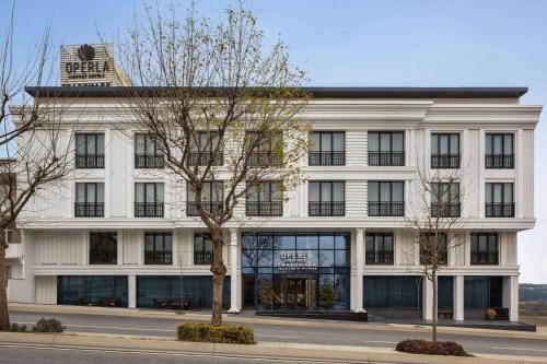 a white building with black windows on a street at Operla Airport Hotels, Trademark Collection by Wyndham in Arnavutköy