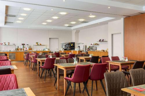 a dining room with tables and red chairs at Amedia Express Passau, Trademark Collection by Wyndham in Passau