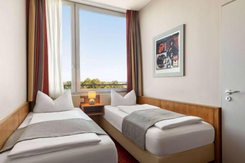 two beds in a room with a window at Amedia Express Passau, Trademark Collection by Wyndham in Passau