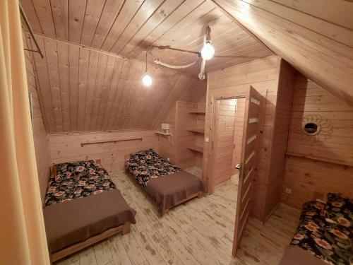 a bedroom with two beds in a room with wooden walls at Domki przy Młynie " Koło Młyńskie " in Krościenko