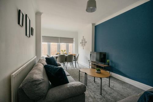 a living room with a couch and a blue wall at Canterbury House By Horizon Stays in Redcar