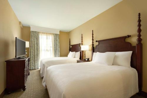 a hotel room with two beds and a television at Embassy Suites Savannah Historic District in Savannah