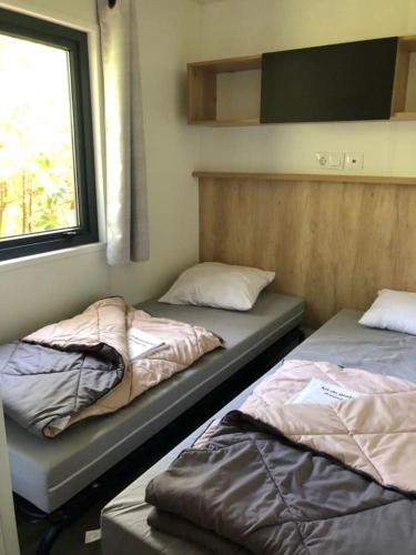 deux lits assis dans une pièce avec une fenêtre dans l'établissement Mobilhome au calme proche forêt, à Biscarrosse