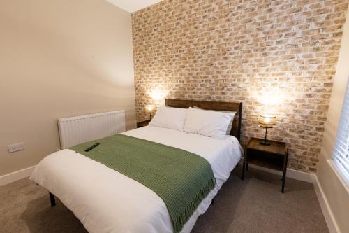 1 dormitorio con cama y pared de ladrillo en Newly Renovated Family and Workspace Business Home in Runcorn, Cheshire ENTIRE HOUSE, 