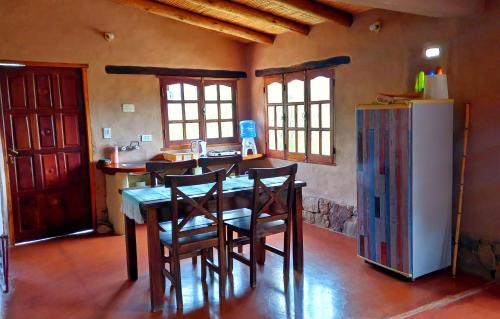a kitchen with a table with chairs and a refrigerator at MAMAICUNA CABAÑA in Tilcara