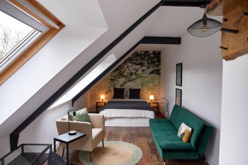 een slaapkamer op zolder met een bed en een groene bank bij La Breizhidence in Combourg