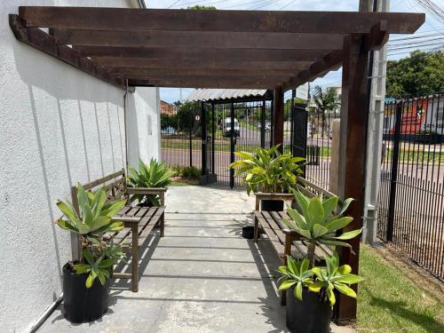 uma pérgola de madeira com bancos e vasos de plantas em Pousada Recanto da Palmeira em Guaíba