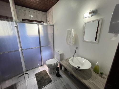 a bathroom with a shower and a toilet and a sink at Pousada Recanto da Palmeira in Guaíba