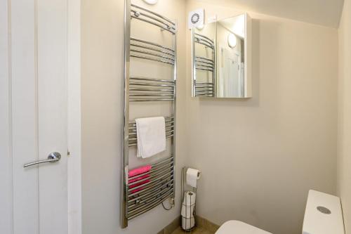 La salle de bains est pourvue de toilettes et d'un miroir. dans l'établissement Poet's Cottage by StayStaycations, à Aberdare