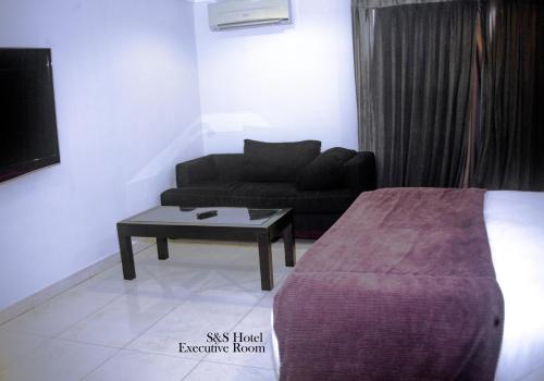 a room with a bed and a couch and a table at S & S Hotel & Suites in Lagos
