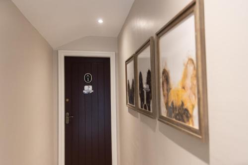 a hallway with a black door and framed pictures at The Dog in Over Peover in Knutsford