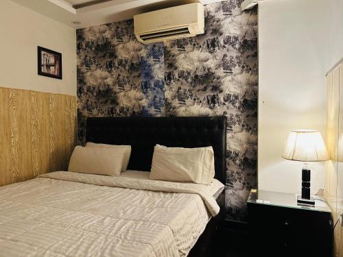 a bedroom with a bed and a wall with wallpaper at Hotel SeaView 2 in Karachi