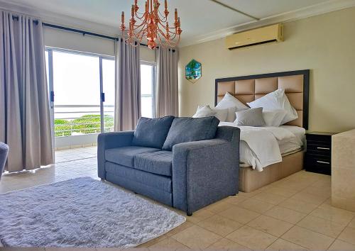 um quarto com uma cama e um sofá azul em Glen Ashley Beach Villas em Durban