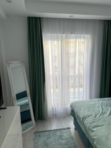 a bedroom with a mirror and a bed with green curtains at Adagio apartment in Creţuleasca