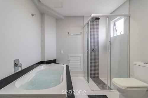 a bathroom with a bath tub and a toilet at Apto lindo prox do mar em Balneário YVD1301 in Balneário Camboriú