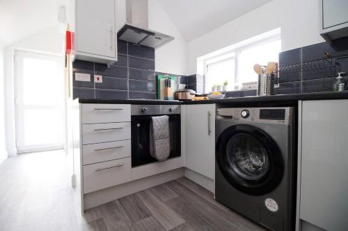 a kitchen with a washer and a washing machine at Modern Guesthouse, Fast Wi-Fi, Street Free Parking, Central, Fully Equipped in Cardiff
