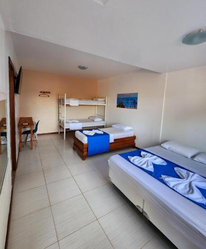 a bedroom with two beds and a desk and a table at Pousada Suítes do Atlântico in Ilhéus