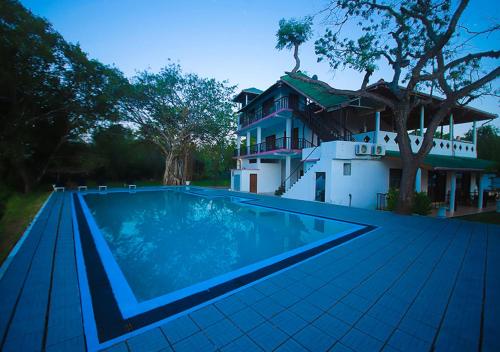 a swimming pool in front of a house at Birdsong Leisure Resort in Tissamaharama