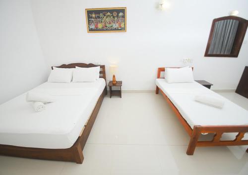 two beds in a room with white walls at Birdsong Leisure Resort in Tissamaharama