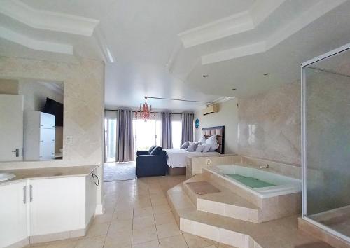 a large bathroom with a tub and a bedroom at Glen Ashley Beach Villas in Durban