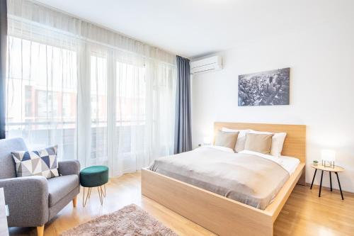 布達佩斯的住宿－LOTUS Apartments ORIGO with Garage，一间卧室配有一张大床和一把椅子