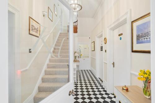 un pasillo con escaleras blancas y suelo blanco y negro a cuadros en Kingston House en Torquay