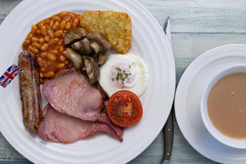 a plate of food with eggs bacon beans beans and a cup of coffee at Kingston House in Torquay