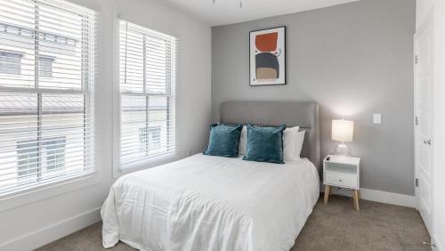 Dormitorio blanco con cama con almohadas azules en Landing Modern Apartment with Amazing Amenities (ID4314X66), en Charleston