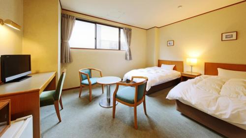 a hotel room with two beds and a desk at Konya in Matsue