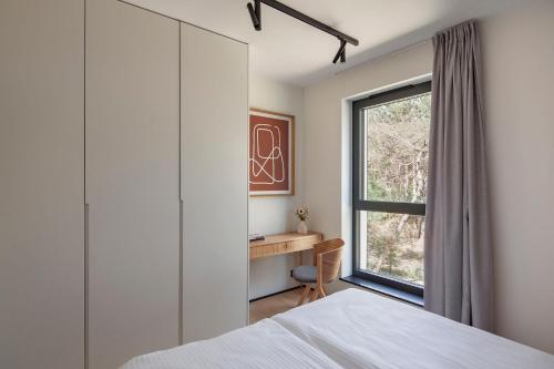 a bedroom with a window and a desk at Apartamenty na Półwyspie Wydma&Las in Jastarnia