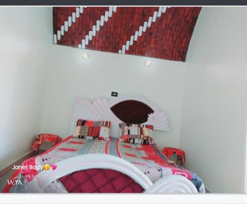 Schlafzimmer mit einem roten und weißen Bett und einem Spiegel in der Unterkunft Roma House in Assuan