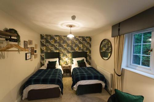 two beds in a room with green and white at The Dog in Over Peover in Knutsford