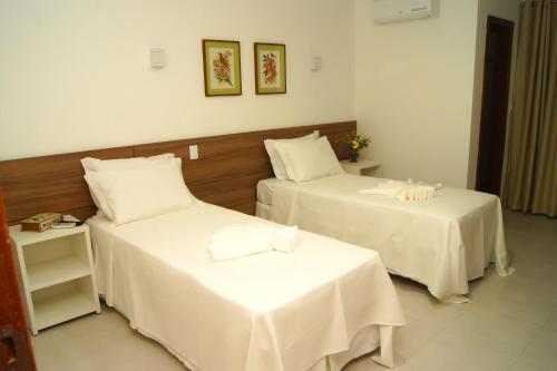 a hotel room with two beds with white sheets at Hotel Flor Da Chapada in Itaberaba