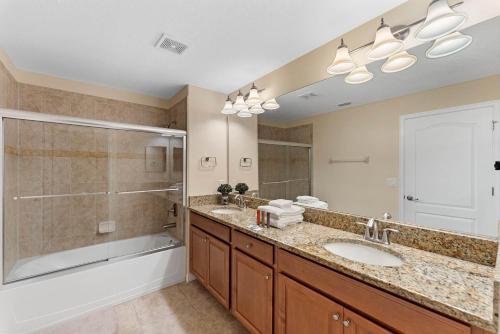 een badkamer met 2 wastafels, een douche en een bad bij 5 Bedrooms 4 Bathrooms Storey Lake 4819 Ct in Kissimmee