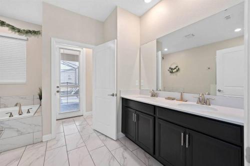 a bathroom with a double sink and a tub and a shower at Magic Marvel Getaway in Kissimmee