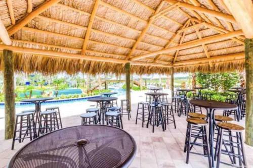 a patio with tables and chairs under a straw roof at Magic Marvel Getaway in Kissimmee
