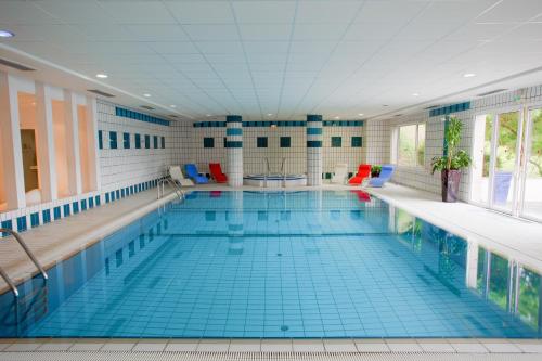 a large swimming pool with a blue tile floor at Hôtel Spa Du Béryl in Bagnoles de l'Orne