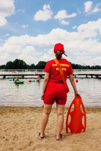 a woman standing on the beach with a life preserver at Ośrodek Wypoczynkowy Kalwa in Pasym
